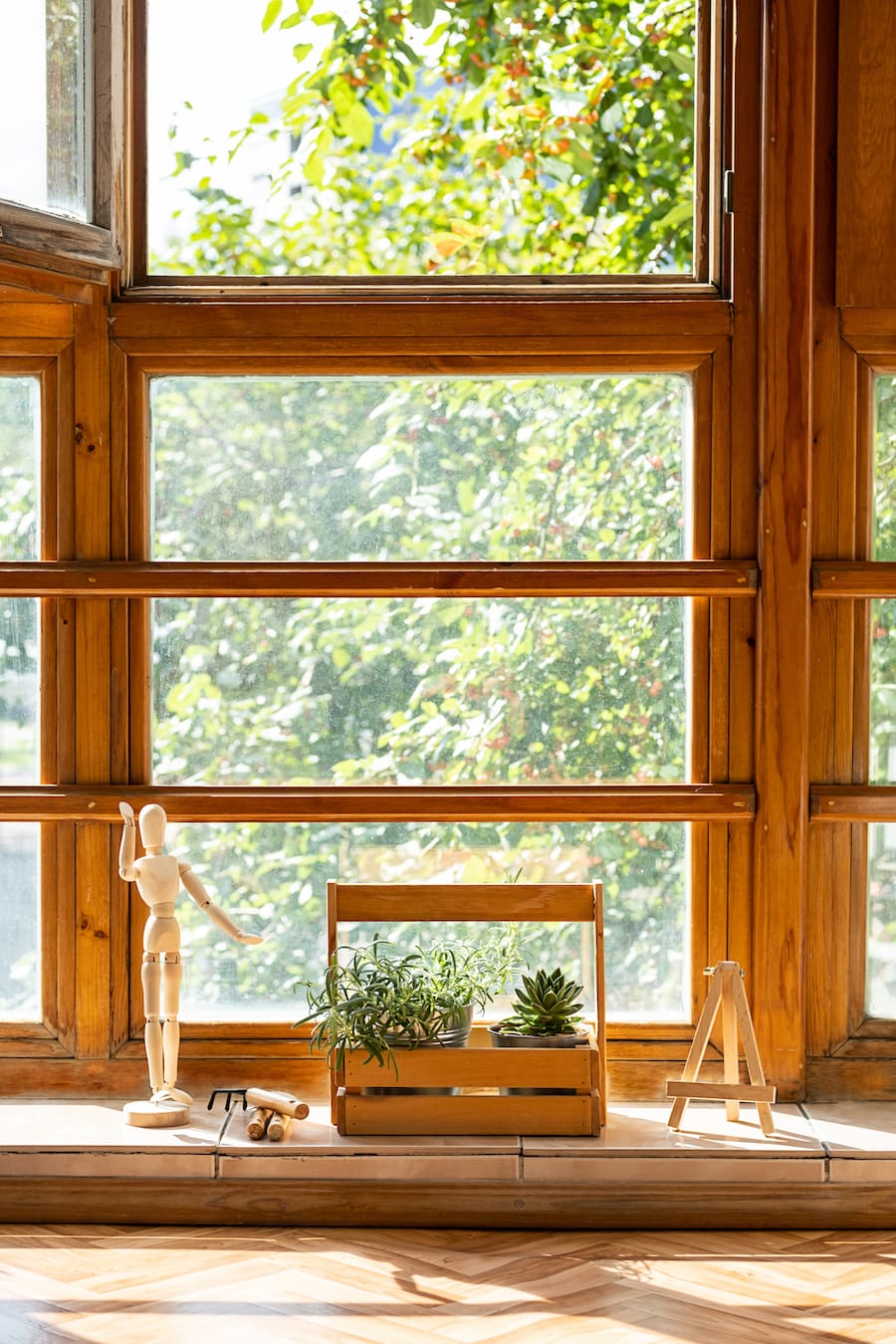 Sunny glass and wooden balcony with potted houseplant.