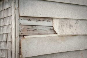 Cracked siding panels with visible gaps allowing moisture intrusion