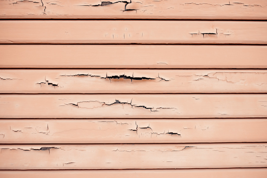 Close-up of cracked and warped siding panels on a home