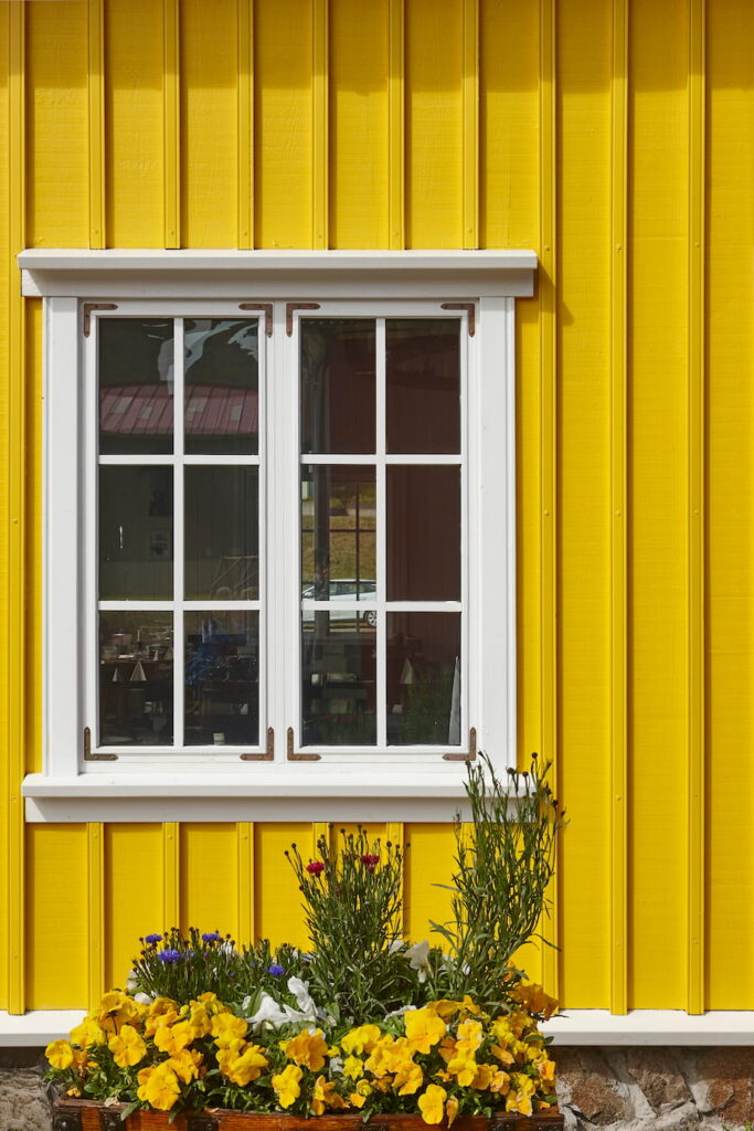 Picturesque yellow wooden facade and white window.